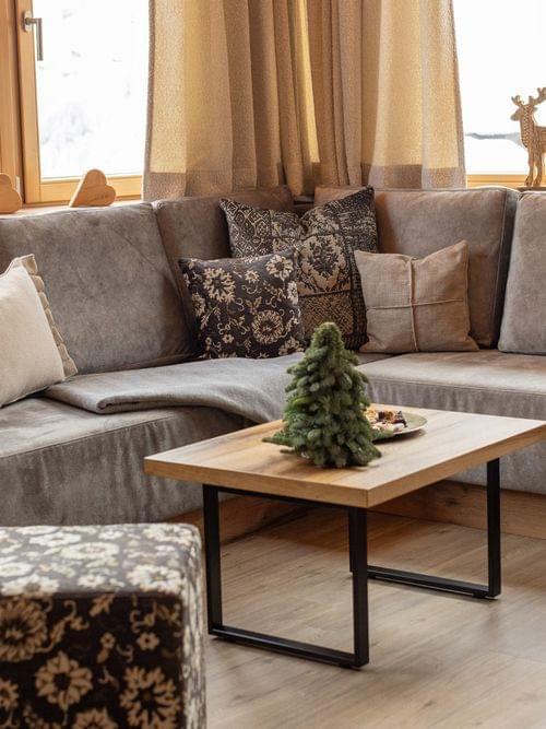 Gemütliches Chalet-Wohnzimmer mit grauem Ecksofa, Holztisch und Winterdekoration