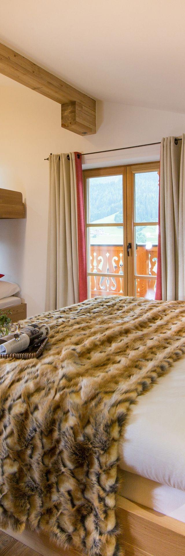 Cozy alpine hotel room with double bed, bunk beds, fur blanket and wooden decor