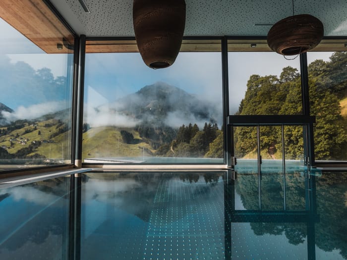 The poolhouse swimming pool with views of the mountains through panoramic windows.