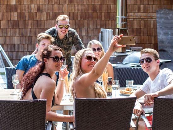 Group of friends taking a selfie while enjoying drinks at an outdoor café