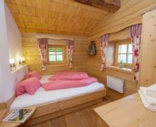 Cozy alpine bedroom with wooden walls, double bed in red checkered bedding, and rustic decor