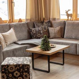 Cozy chalet living room with grey sectional sofa, wooden coffee table and winter decor