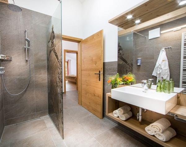 Modernes Hotelbad mit begehbarer Dusche, Holzakzenten und frischen Handtüchern