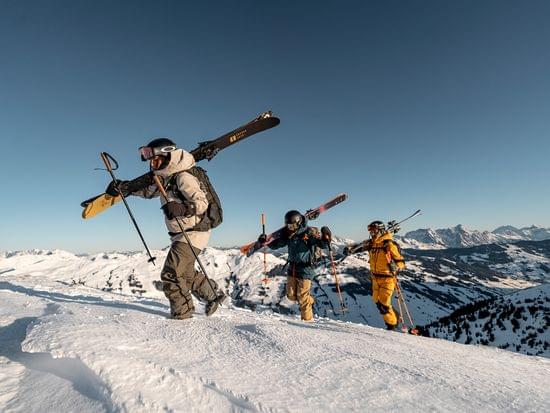 Group of skiers hiking uphill with skis on shoulders in snowy alpine mountains