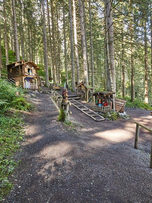 Fairy tale forest path with wooden dwarf houses and sculptures in a pine forest