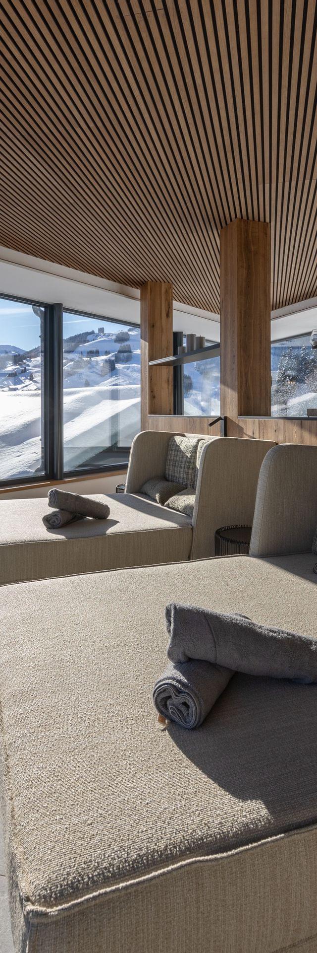 Badehaus Ruheraum mit Großen Liegen und Panoramafenster mit Ausblick auf die Winterlandschaft 