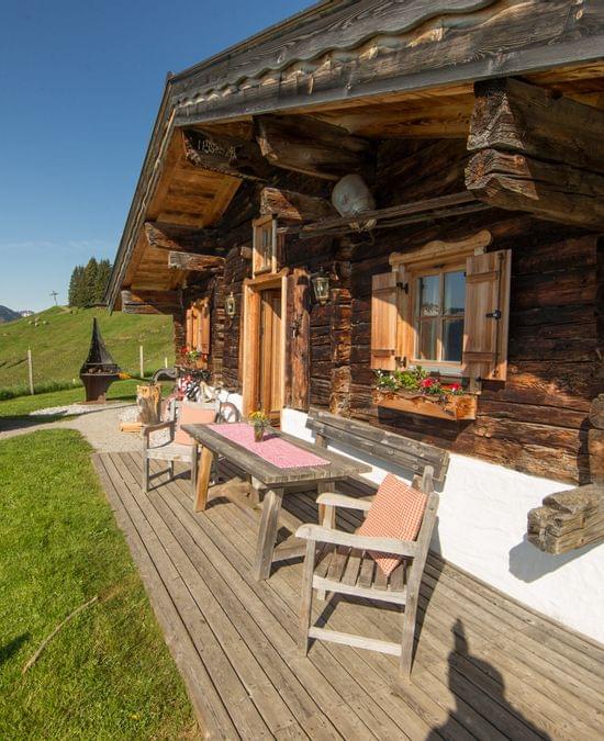 Rustikale Berghütte aus Holz mit Sitzbereich, Hot Tub und Alpenblick im Sommer
