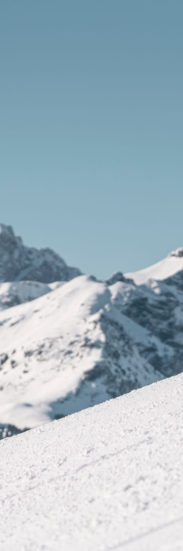 3 Frauen beim Skifahren, Klatschen mit den Händen ein. Im Hintergrund Tief verschneite Berge 