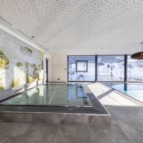 Badehaus Kinderbereich, Kinder-Wasserbecken mit Fischen an der Wand und Ausblick auf die Verschneite Bergwelt 