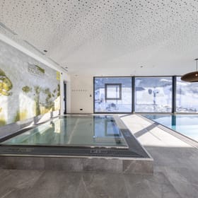The kids’ area in the bathhouse, featuring a children’s pool with fish on the wall and views of the snow-covered mountains.