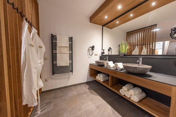 Modernes Spa-Badezimmer mit Steinausguss, gerollten Handtüchern und Holzakzenten