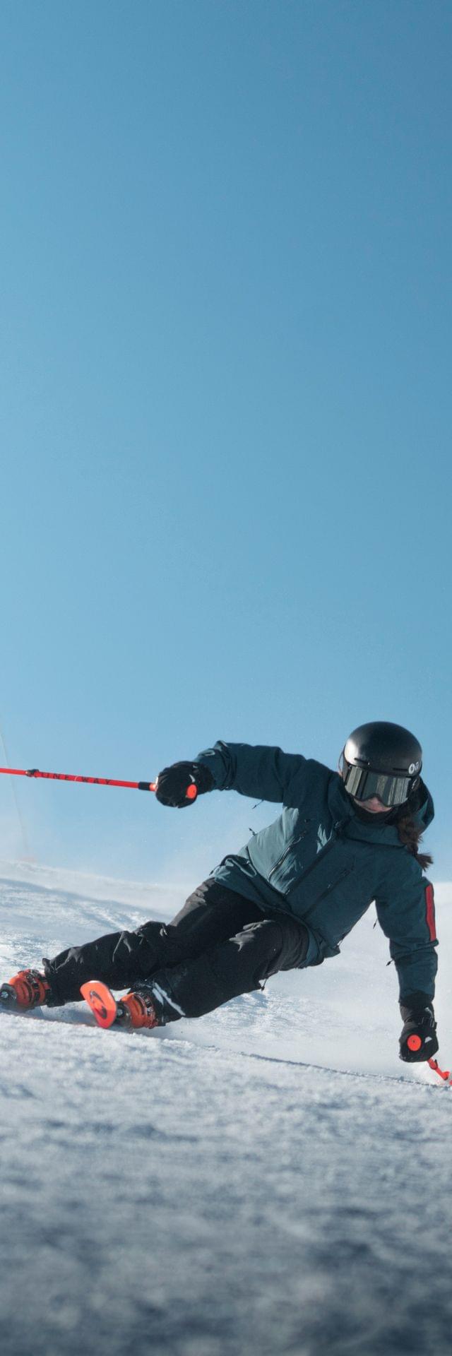 Three skiers in winter gear carving down a sunny slope on a clear blue sky day