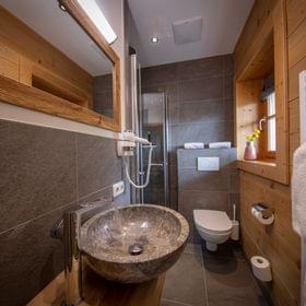 Modern rustic bathroom with stone sink, wooden walls and walk-in shower