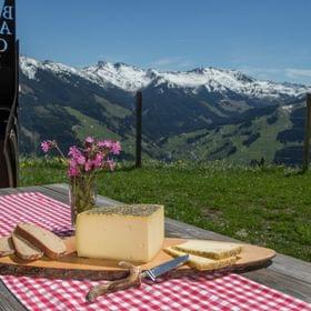 Alpkäse und Brot auf Holztisch mit Bergblick in den österreichischen Alpen