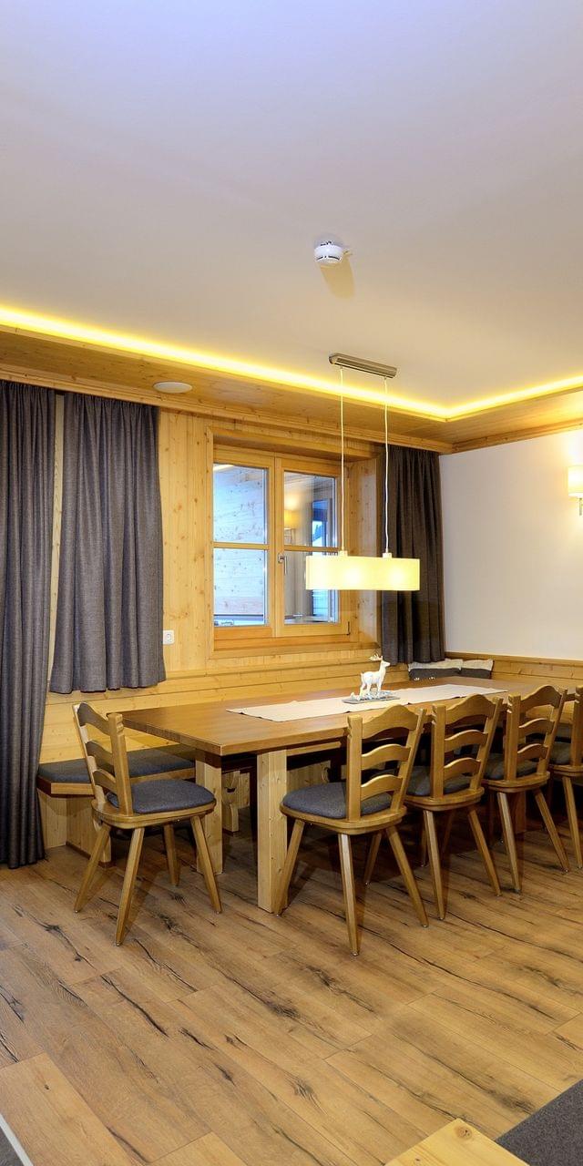 Cozy alpine chalet dining and living area with wooden furniture and mountain view