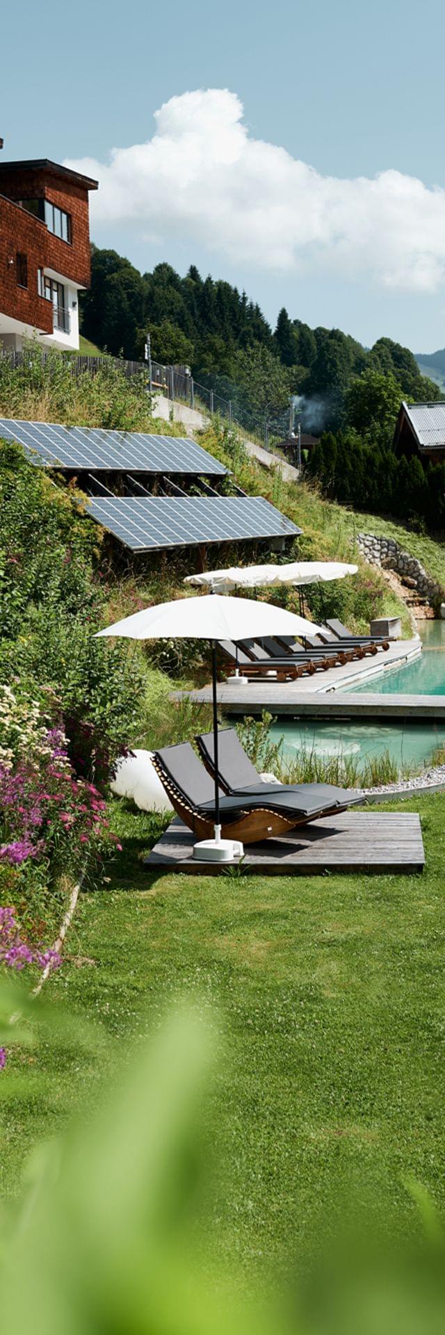 Eco resort with solar panels, natural pool, lounge chairs and mountain views