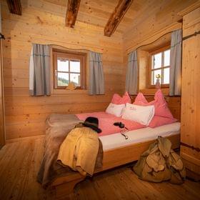 Gemütliches Alpenzimmer mit Holzmöbeln, rosa Karo-Bettwäsche und traditioneller Dekoration