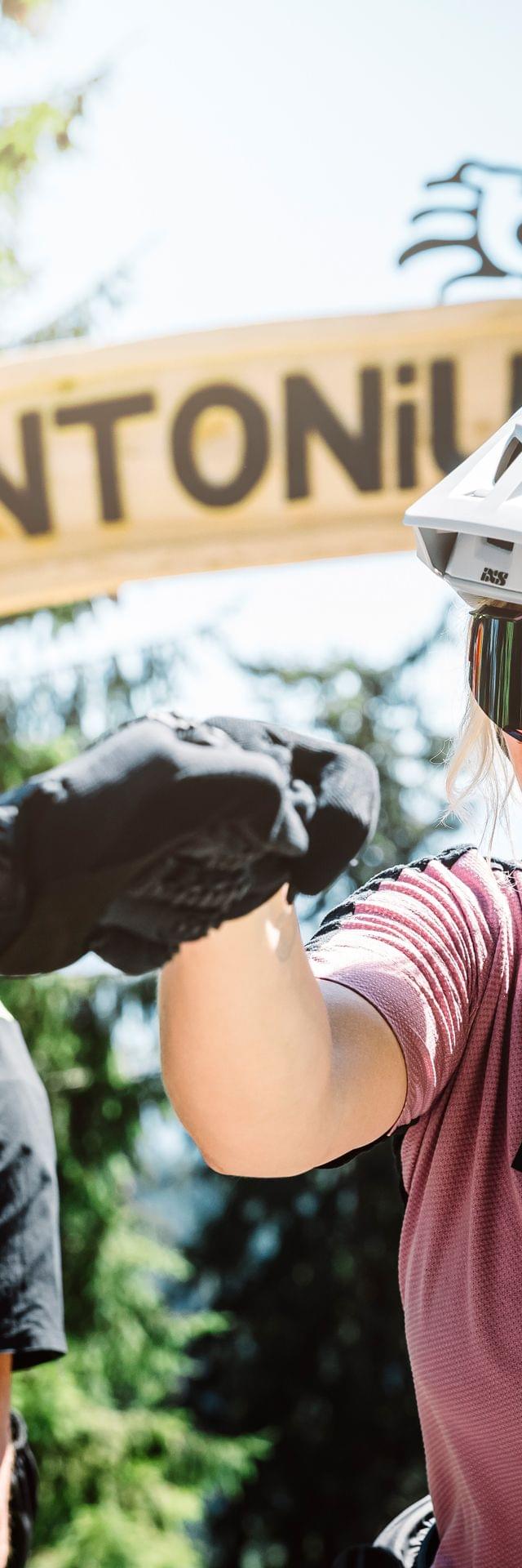 Mountainbiker lächeln und geben sich einen Fistbump am Eingang des Antonius Trails