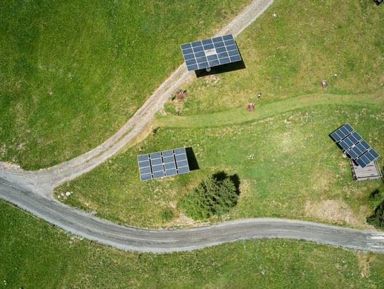 Aerial view of solar panels on grassy field near winding country road