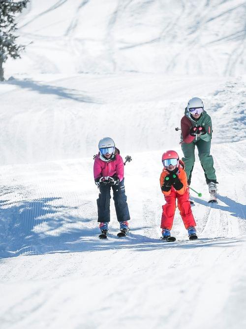 Familie fährt an einem sonnigen Wintertag gemeinsam Ski in den verschneiten Bergen
