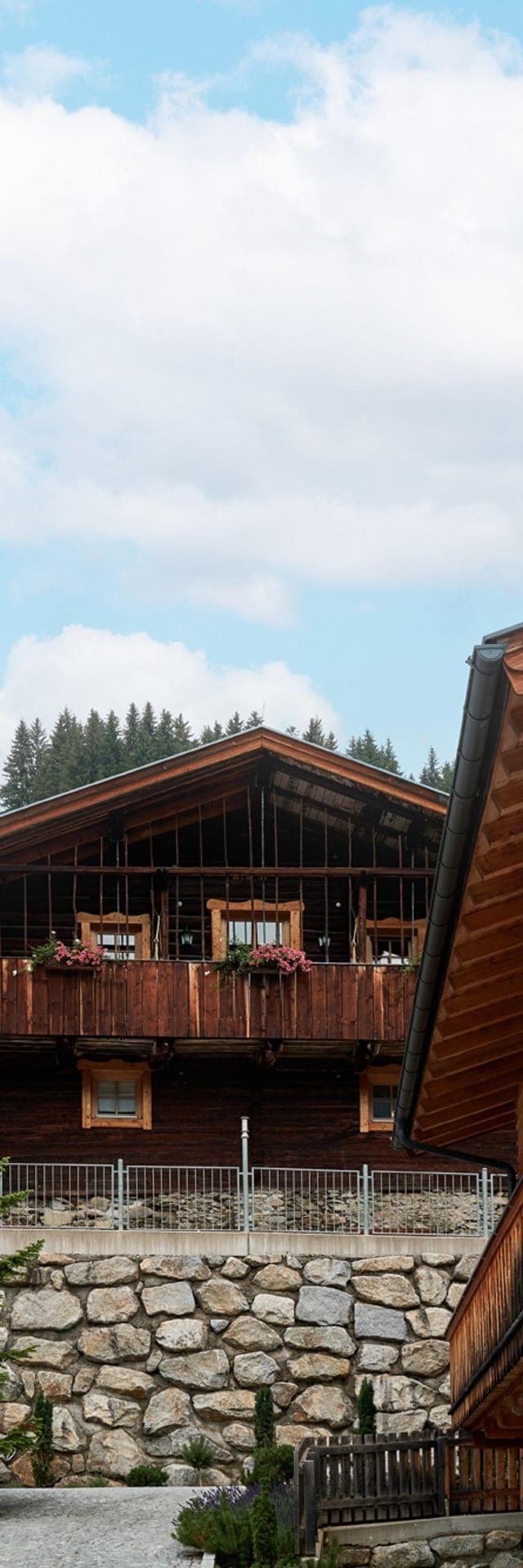 Wooden alpine chalets with flower balconies and mountain forest backdrop