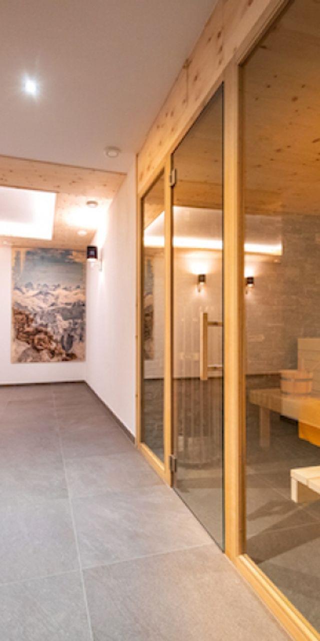Moderner Wellnessbereich mit Holzsauna, gefliestem Boden und Wandkunst