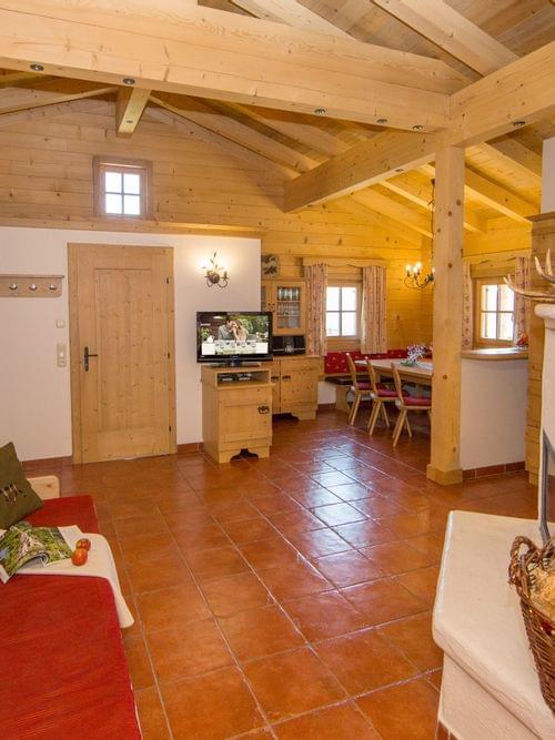 Cozy alpine living room with wooden interior, tiled floor, and traditional fireplace