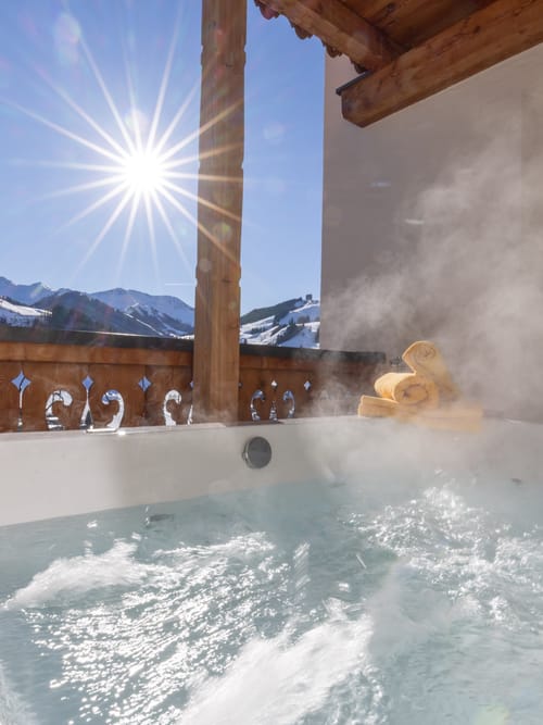 A bubbling hot tub with a view of the snow-covered mountains.