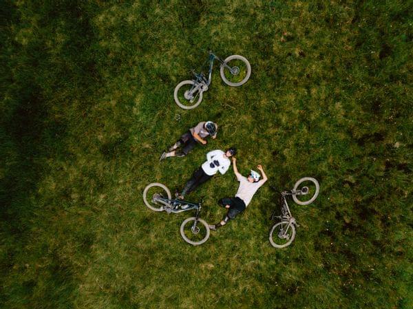 3 Biker mit ihren Bikes in der Wiese liegend, genießen einen Sommertag 