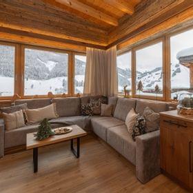 Cozy alpine lodge living room with wooden interior and panoramic snowy mountain view
