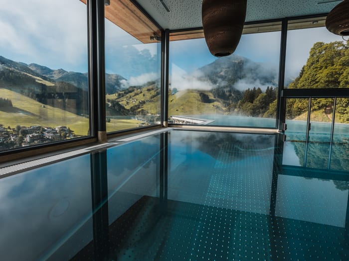The poolhouse swimming pool with views of the mountains through panoramic windows.