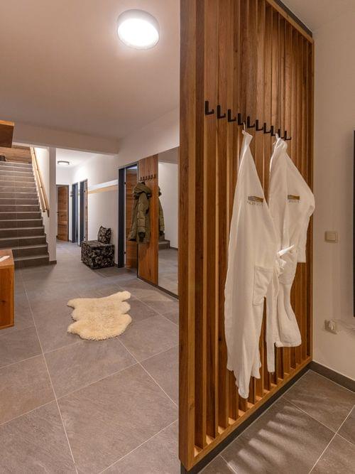 Modern spa changing room with wooden accents, bathrobes, towel warmer and staircase