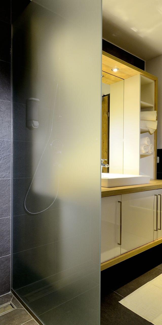Modern bathroom with walk-in shower and wooden sauna cabin