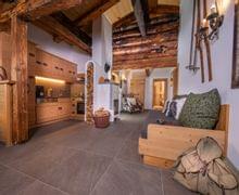 Cozy alpine living room with rustic wood furniture, a small kitchen, and a fireplace