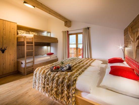 Zimmer mit Doppelbett und Stockbett, Hochwertig mit Holz verkleidet, Rote Akzente und in Alpinem Chic 