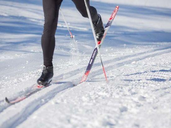 Langläufer gleitet mit Skistöcken über präparierte Schneespur