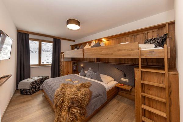 Cozy alpine hotel room with double bed and wooden bunk beds in winter setting