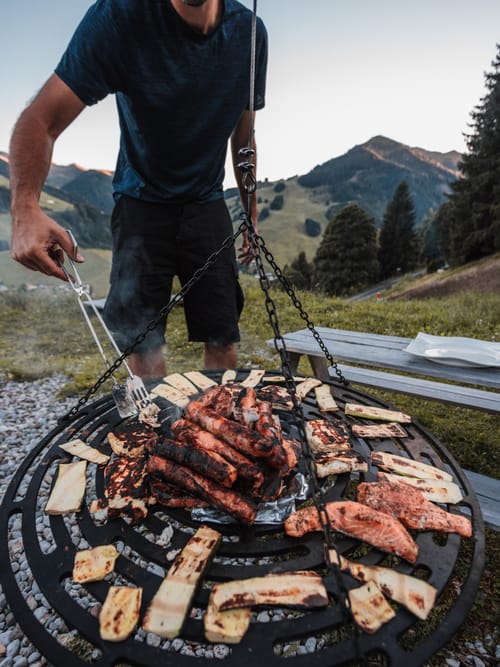 A man using tongs to turn food on the grill.