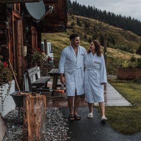 2 Personen in Bademänteln vor der Almhütte, Herbstliche Stimmung im Hintergrund 