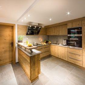 Modern wooden kitchen with built-in appliances, island counter, and fresh vegetables on the counter
