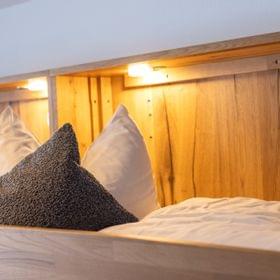 Cozy wooden bunk bed with soft white and gray pillows under warm lighting