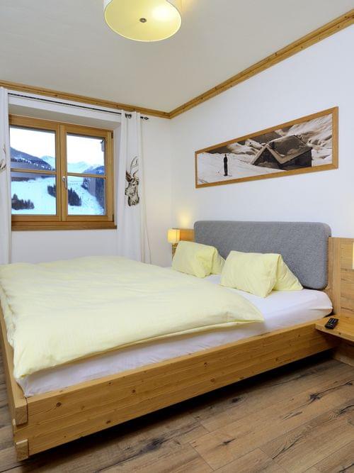 Gemütliches Alpen-Hotelzimmer mit Holzmöbeln, Doppelbett und Bergblick