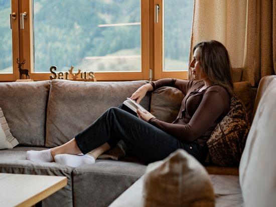 Frau auf Couch genießt den Blick durch die Panorama Fenster 