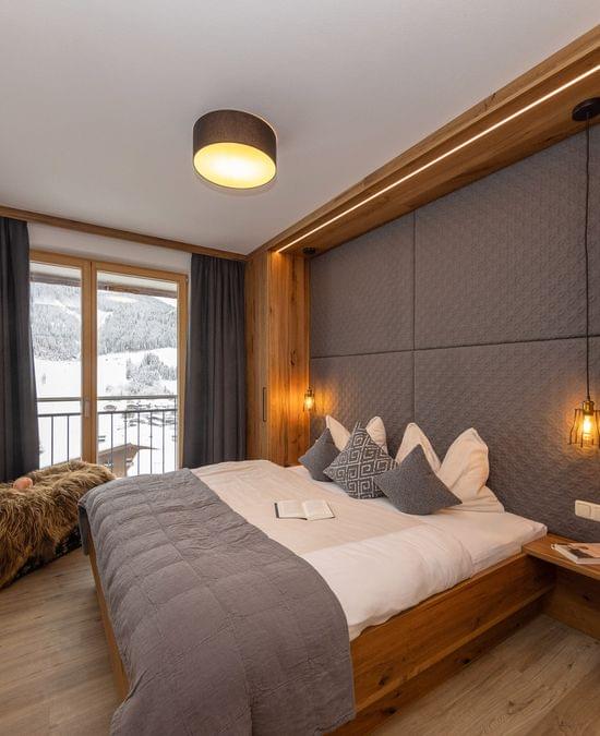 Cozy hotel bedroom with wooden furnishings, mountain view, and modern lighting