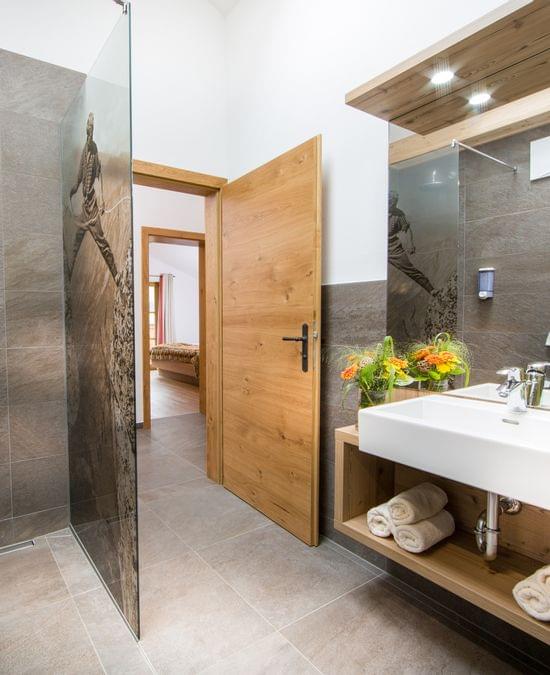 Modernes Hotelbad mit begehbarer Dusche, Holzakzenten und frischen Handtüchern