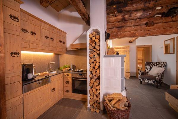 Cozy rustic kitchen with wood cabinets, firewood stack and traditional stove