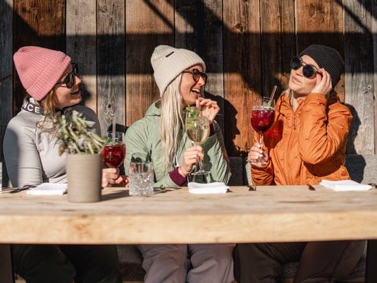 3 Frauen auf einer Bank mit Sonnenbrillen und Drinks in der Hand 