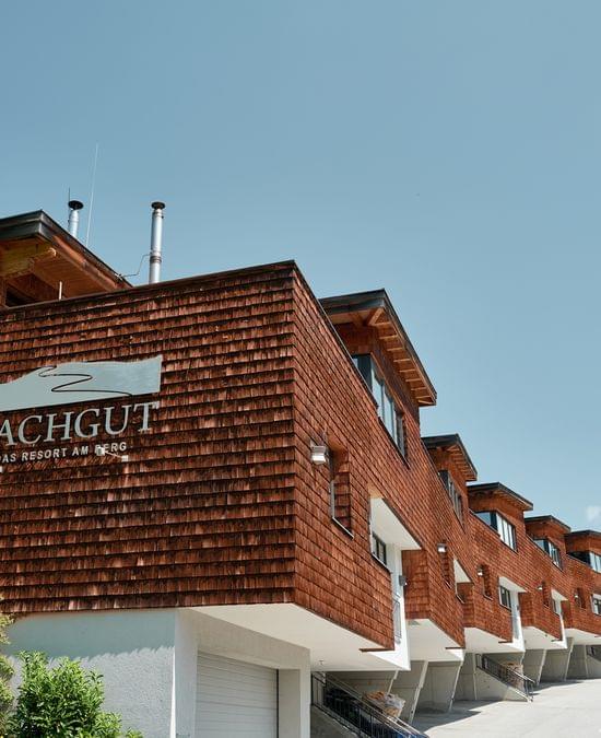 Bachgut Berghotel mit Holzfassade und malerischer Hanglage unter klarem blauen Himmel