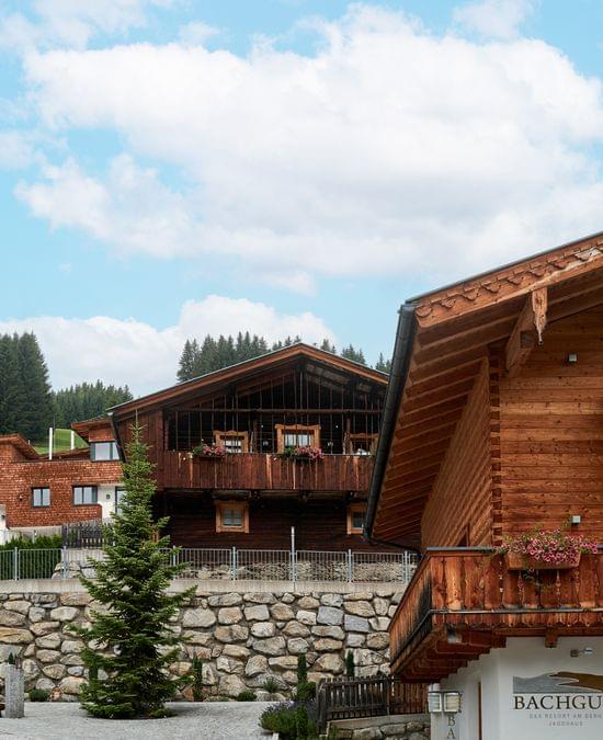 Alpine Holzchalets mit Blumenbalkonen vor bewaldeter Berglandschaft