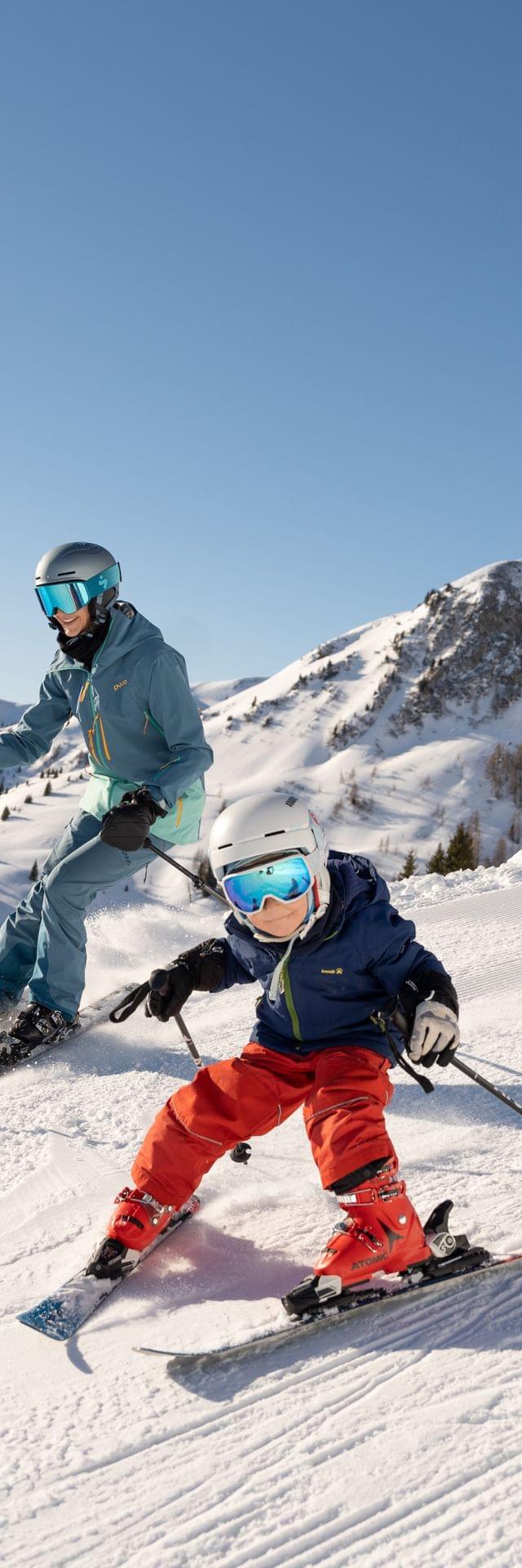 Familie fährt Ski auf präparierter Piste in sonnigem alpinem Skigebiet